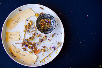 Autumn dried plants and flower on the plate on the blue background