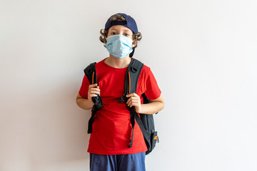 Obraz premium Little boy, elementary school student, going to school with a backpack. New normality at coronavirus, covid-19, time wearing a safety mask. School reopening concept.