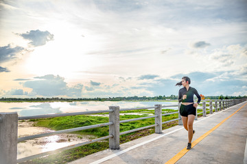 runner - woman running outdoors training for Exercise run.At the bridge at sunset. © Chanchai