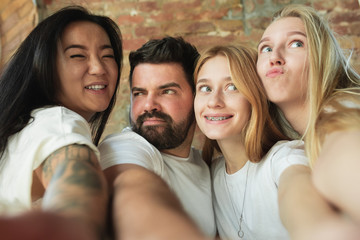 Taking selfie together. Group of adorable multiethnic friends having fun at home. Copyspace. Diversity, inclusion, friendship and love concept. Different nationalities united with sincere emotions.