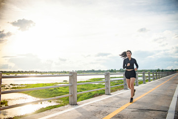 runner - woman running outdoors training for Exercise run.At the bridge at sunset. © Chanchai