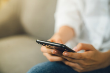 Young woman hand holding smartphone and chatting with friends at social network on the table.