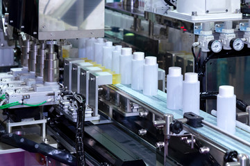 white plastic bottle moving on conveyor belt of auto capping and labeling machine at cosmetic and skin care manufacturing. cosmetic industry and ai technology machinery concept.