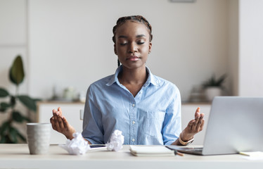 Coping With Stress At Work. Young African Businesswoman Meditating In Office