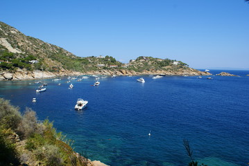 Fototapeta na wymiar A bay in Giglio Island: the rocky coast and boats off the coast