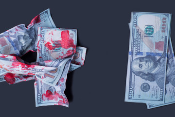 on a black background close-up crumpled bloodied dollar bills next to new money
