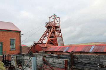 Big Pit was a working coal mine from 1880 to 1980. It is now obsolete and closed. Exterior of an old building with broken and discarded machinery scattered on the ground.

