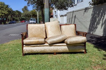 A broken settee is left on the sidewalk in an urban street. The dumping of rubbish is an ongoing...