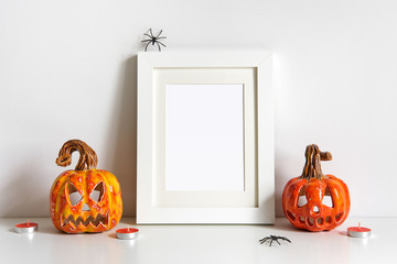 Halloween composition with ceramic pumpkins jack lantern and frame on table wall background. Greeting card template