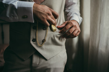 Elegant man with suit. Closeup groom hands holding a pocket watch.