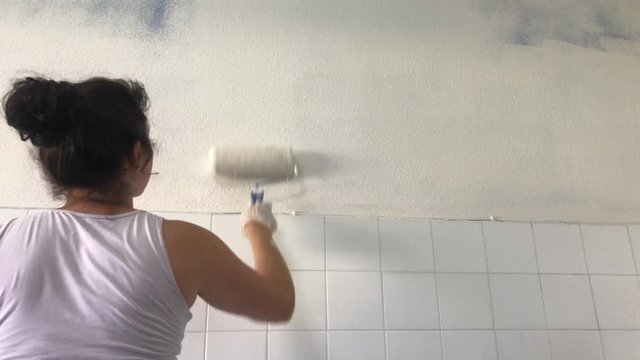 Mujer pintando la pared de su casa