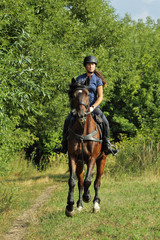 Young woman in uniform and helmet riding horse. Equestrian sport - dressage.