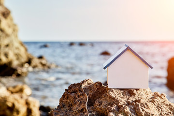 Real estate sale. Luxury beach house. Rental of property. Wooden model of house on sea shore mockup style, copy space