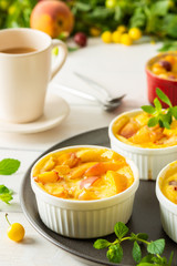 Delicious clafoutis made from white yogurt and peaches, cherry plum and peach dessert in portioned bowls on the table with a cup of juice