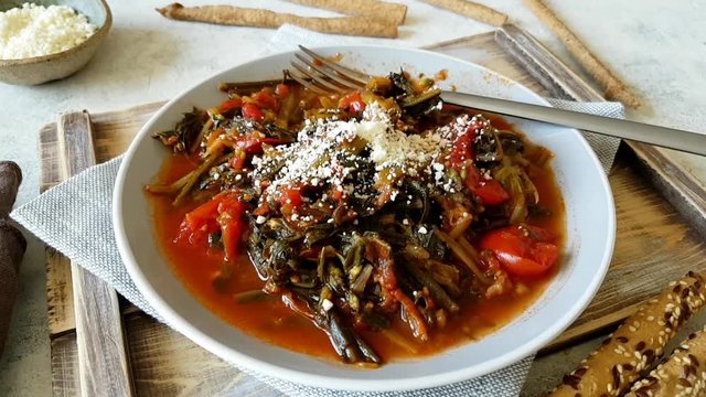 Plate of sauteed green chicory and tomatoes