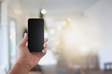 Phone in hand on a blurred background, coffee shop