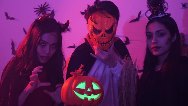 Hand held, normal view, medium shot portrait of group of 3 Asian teens in Halloween costume, posing, treatening at night party. Halloween Party Concept