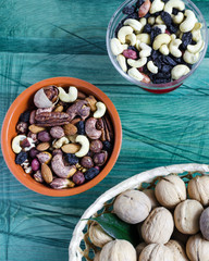 Various types of nuts and raisins in a dish on a wooden green background close up
