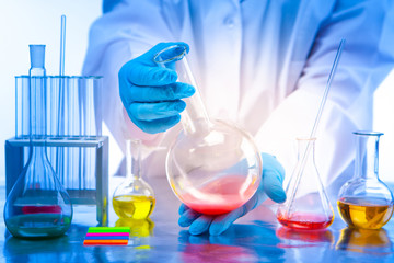 Chemist's hands with a flask close-up. Mixing of chemical reagents. Chemical laboratory equipment. The teacher shows the students an experiment with chemical liquids. Analysis in the laboratory.