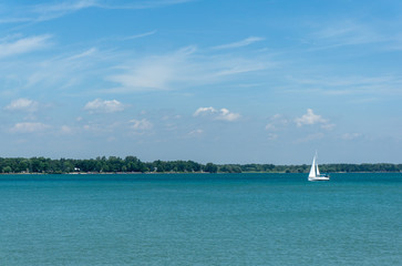 sailboat in distance on a clear blue lake
