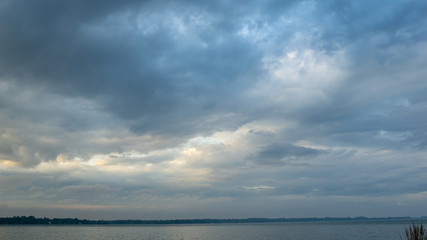 Naklejka na ściany i meble Dark navy clouds over lake