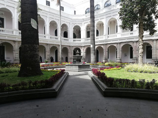 Fototapeta premium Fountain in the middle of the garden in a museum. Pool in the central garden with views of the building, trees and flowers 