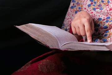 Muslim women's hand reading quran at night 