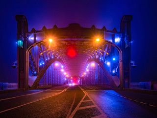 A disturbing night scene. Bridge in the dark. Red and orange warning signals before entering the bridge. Evening lights. The bridge to nowhere.