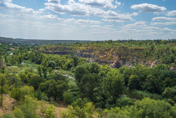 Fototapeta na wymiar Granite quarry in a steppe landscape. Karachunovsky granite quarry on the outskirts of the city of Kryvyi Rih near the reservoir of the Ingulets river.
