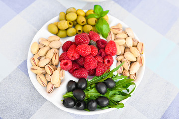 vegetarian snack in the form of raspberries, olives and pistachios