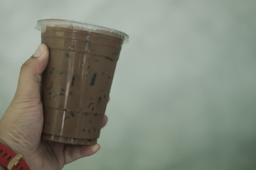 Hand holding iced mocha in plastic cup.