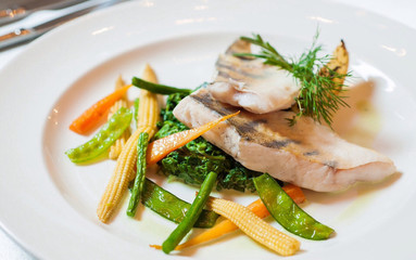 trout fillet with vegetables on a white plate