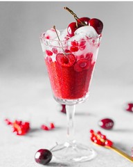 on the table in a tall glass of cherry cocktail with ice