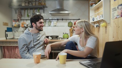Obraz premium Young happy couple talking during breakfast in the kitchen