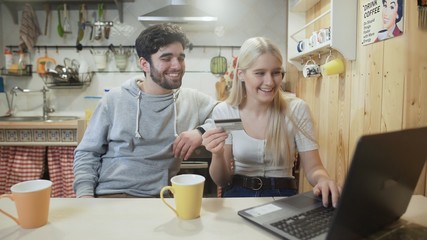 Young man and woman are making an online Shopping Purchase On Notebook
