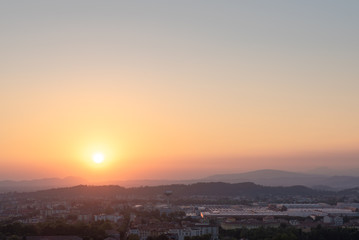 Obraz premium Aerial panoramic sunset view of residential district with buildings of Brescia city and Alps mountain range, blue cloudy sky background, Lombardy, Italy. Brescia Castle.