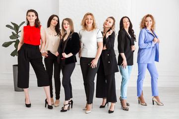 Fototapeta na wymiar A group of women dressed in business style are standing together and posing at the camera.