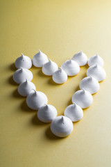 Heart laid out of meringues on a yellow background