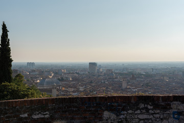 Aerial panoramic sunset view of residential district with buildings of Brescia city and Alps mountain range, blue cloudy sky background, Lombardy, Italy. Brescia Castle.