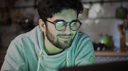 Close up of freelancer working on laptop in kitchen at home at night