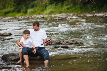 Father teaching son how to fly-fish in river