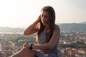 Fototapeta na wymiar Beautiful girl on the roof terrace with aerial view of the old Italian city Brescia at sunset.