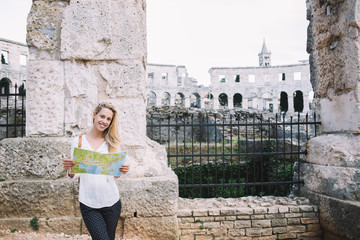 Happy female traveler with paper map in ancient Colosseum in Italy