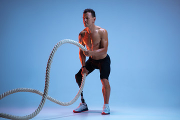 Athlete with disabilities or amputee isolated on blue studio background. Professional male...