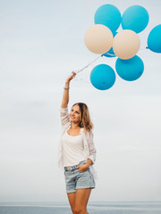 Young woman holding blue and white helium balloons