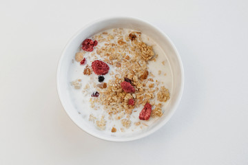 Muesli bowl with milk on white background.