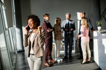 African American businesswoman standing and using mobile phone in the modern office