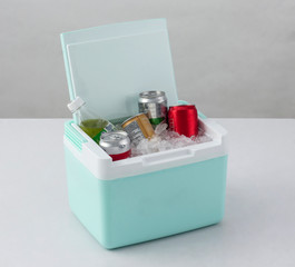 Opened green cooling box with bottles of beverage and ice isolated on white