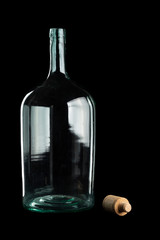 A large, green bottle with a cork on the table against a black background.
