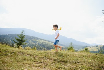 Child pilot aviator with airplane dreams of traveling in summer in nature.